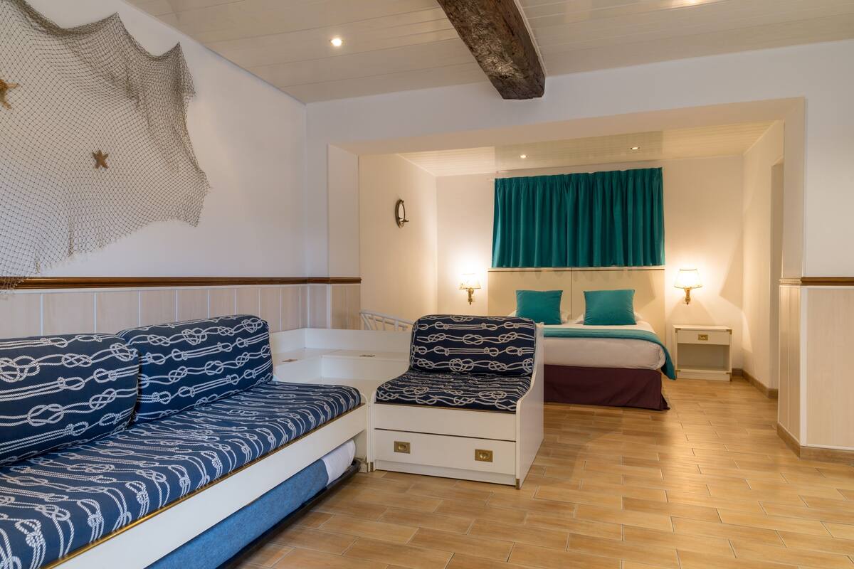 A room with a sofa, a chair, a bed, and a nightstand.