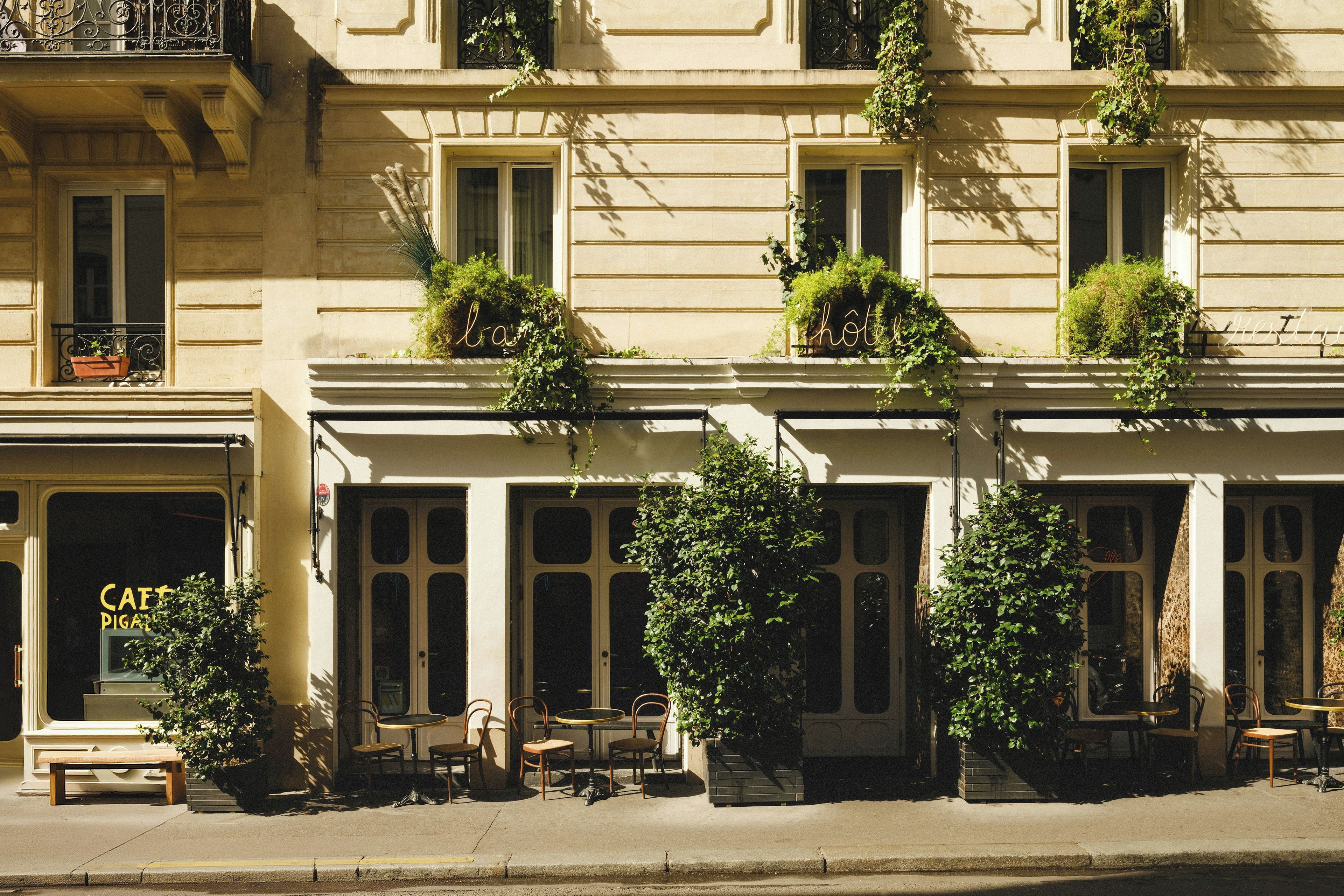 Un edificio con varias ventanas, algunas con plantas, y asientos al aire libre.