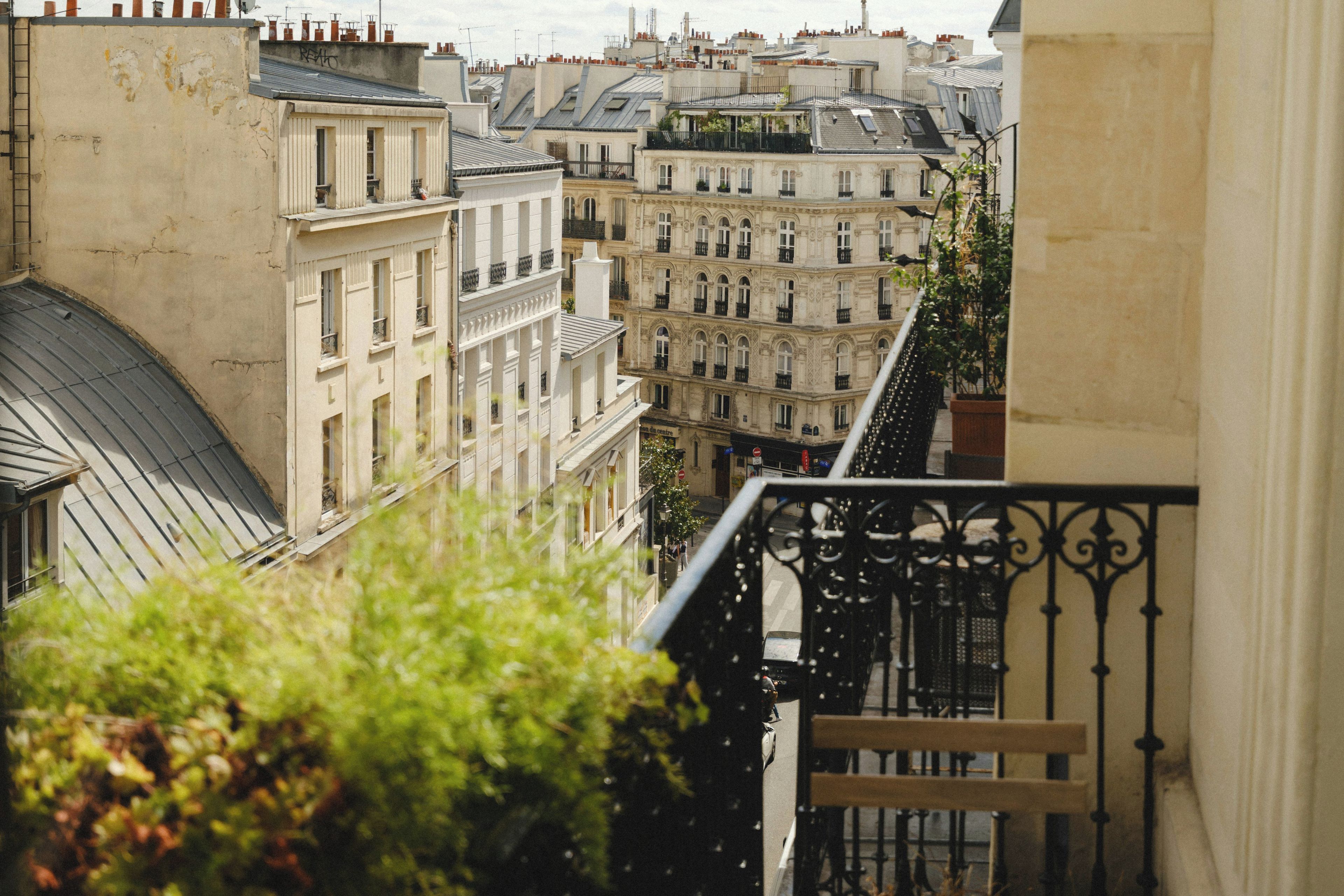 Blick auf eine Stadtlandschaft mit mehreren Gebäuden, darunter ein Gebäude mit einem Balkon und ein Gebäude mit einer Dachbegrünung.