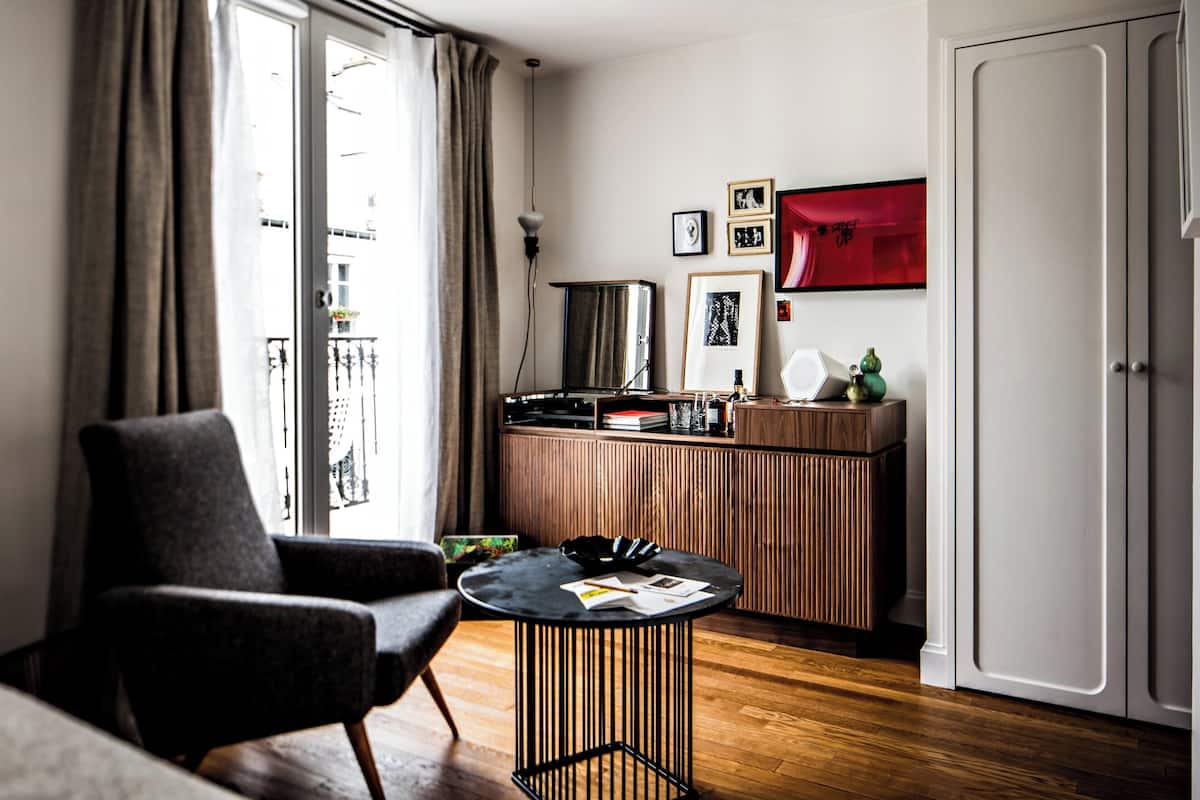 Una sala moderna con un sofá, una mesa redonda de centro y un mueble de madera.