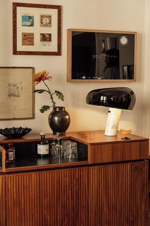 A wooden reception desk with a vase of flowers, a mirror, and framed pictures on the wall. - Le Pigalle, a Member of Design Hotels (Paris)