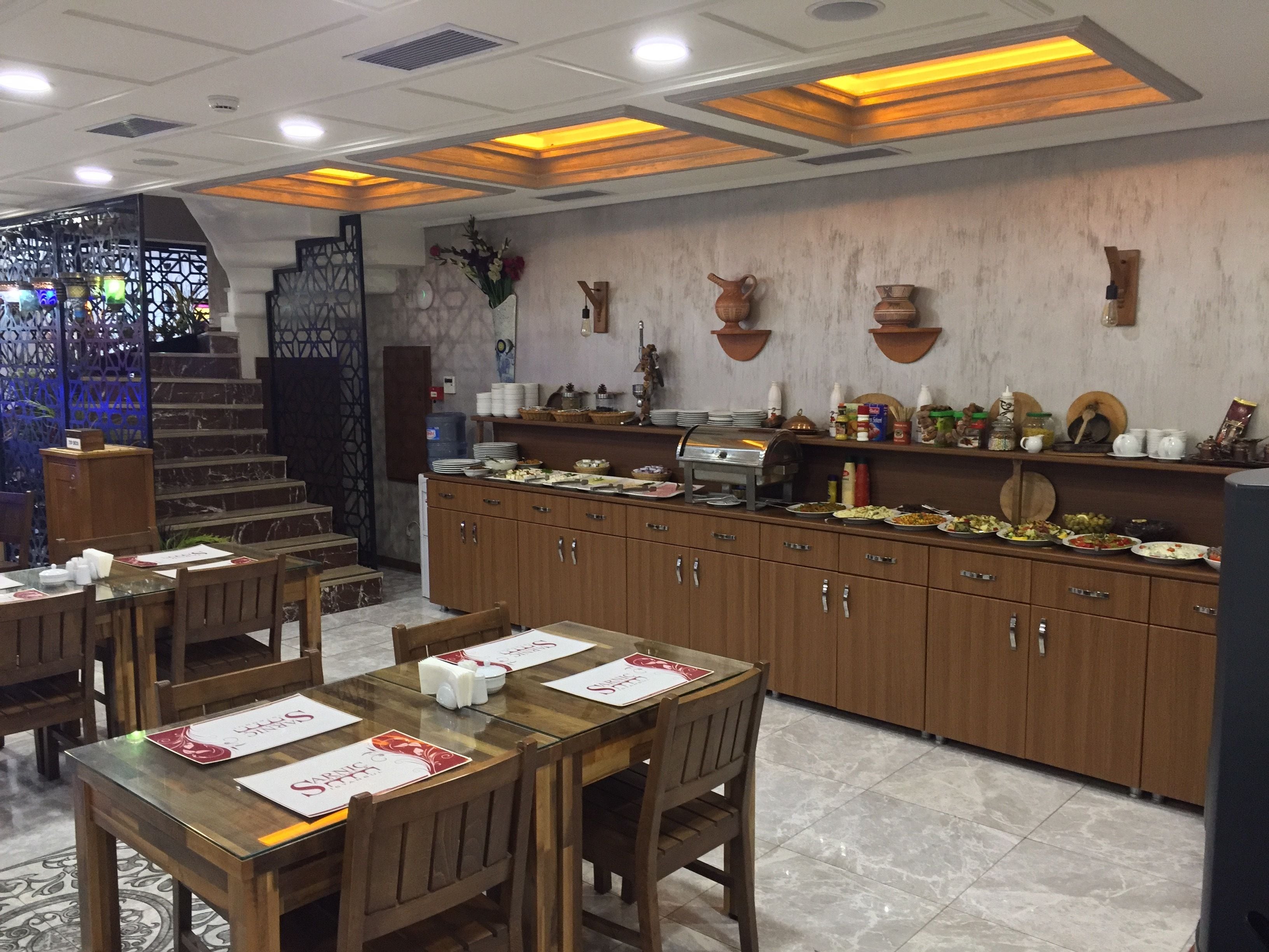 Un restaurante con mesas y sillas de madera, un mostrador de buffet y una escalera que lleva a un nivel superior.