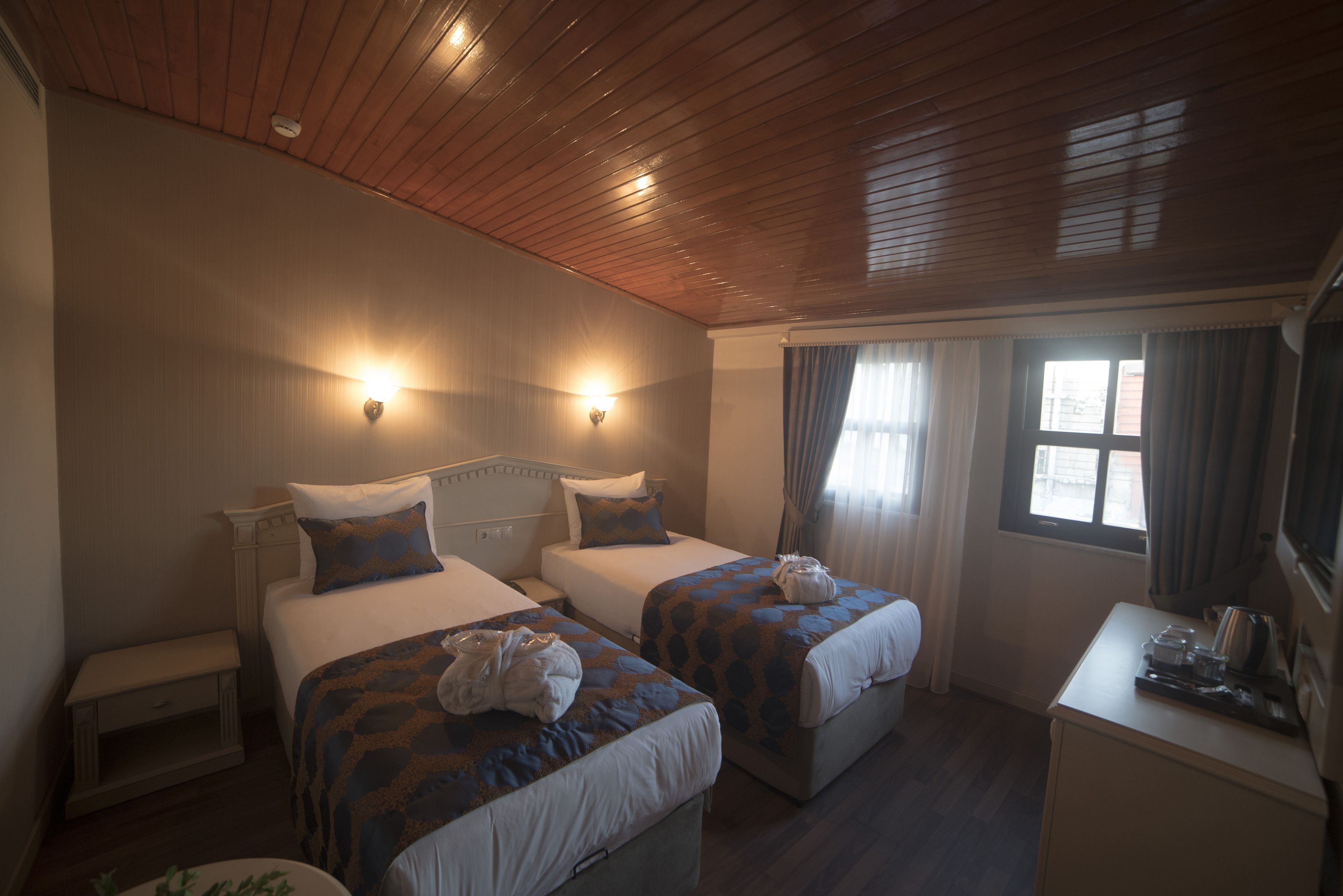 A hotel room with two beds, a desk, and a window with curtains.