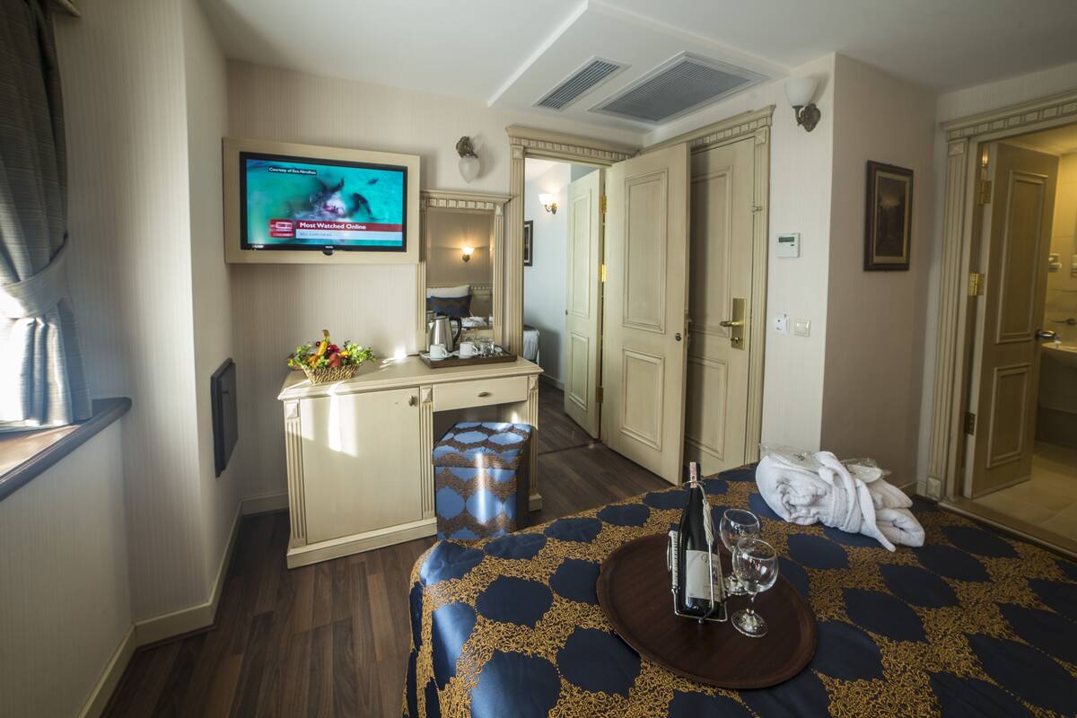 A hotel room with a bed, a desk, a television, and a bathroom visible through an open door.