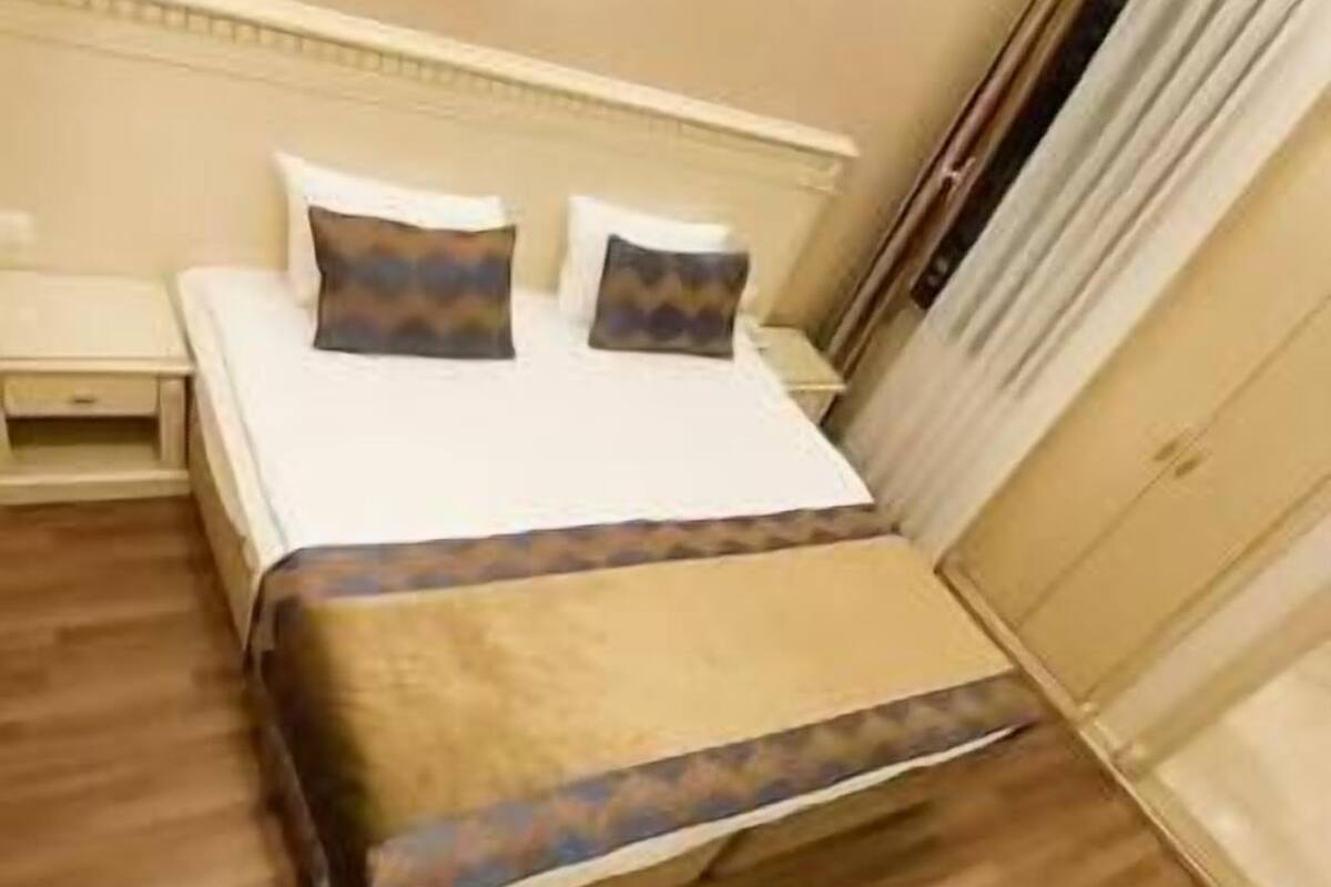 A hotel room with a bed, bedside table, and a wardrobe.