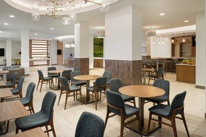 A modern hotel lobby with round tables and chairs, a reception desk, and a bar area. - EVEN Hotel Chicago Tinley Park-Conv Ctr by IHG (Tinley Park)