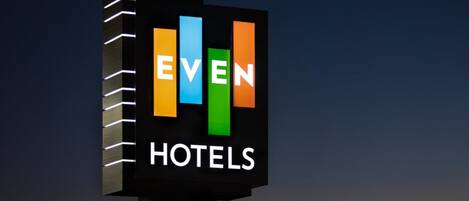 A sign for 'EVEN HOTELS' with a modern design featuring vertical bars in different colors.