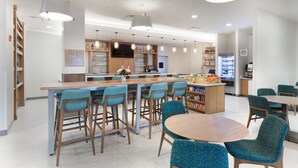 Una cocina moderna con una isla central, taburetes de bar y una mesa redonda con sillas.