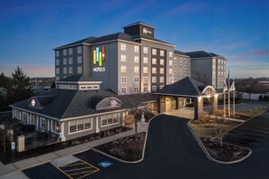 A multi-story hotel with a prominent logo, a covered entrance, and a parking lot. - EVEN Hotel Chicago Tinley Park-Conv Ctr by IHG (Tinley Park)