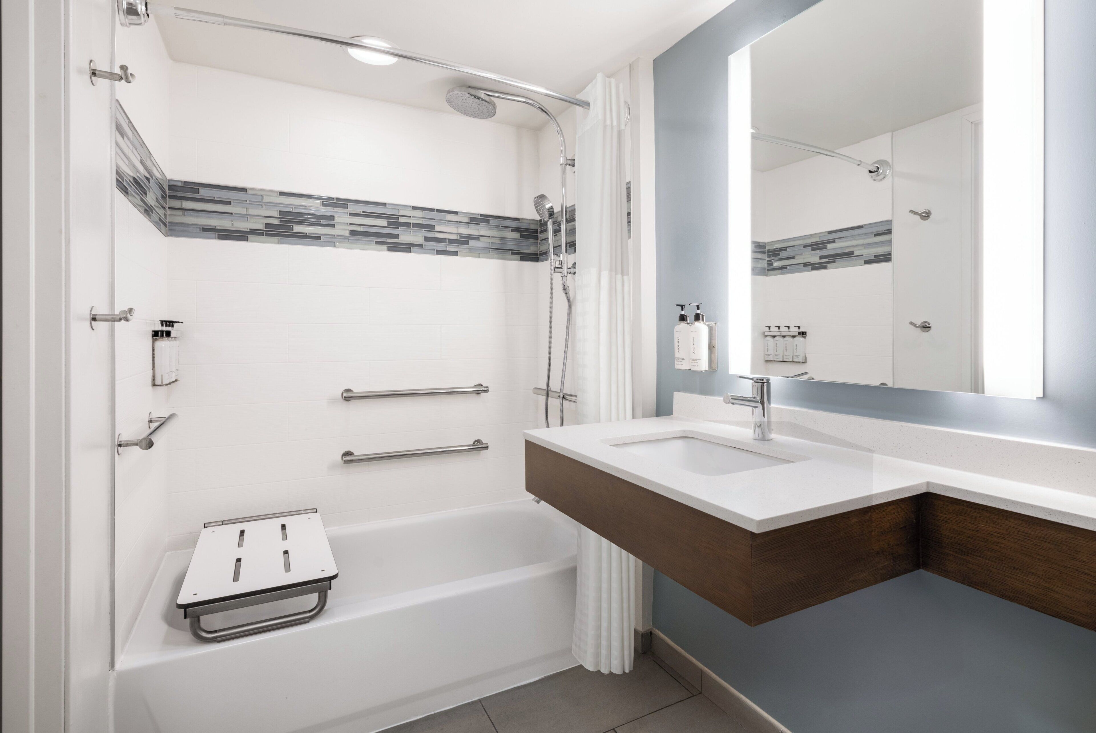 Een moderne badkamer met een bad, douche, wastafel met twee spoelbakken en een grote spiegel.