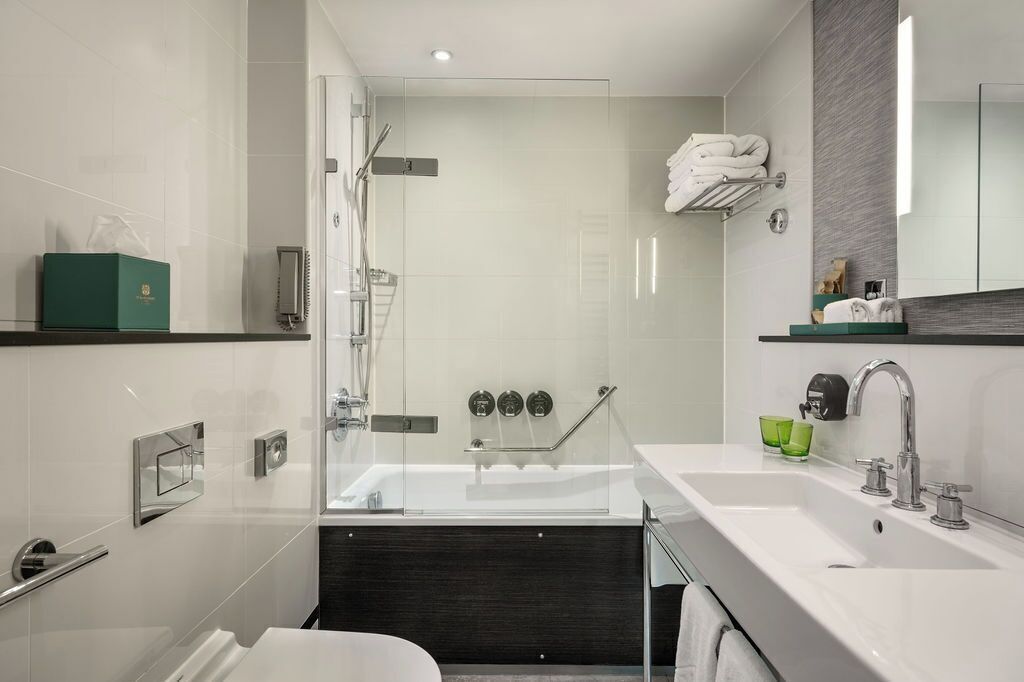 A modern bathroom with a glass-enclosed shower, a large bathtub, and a vanity with a mirror.