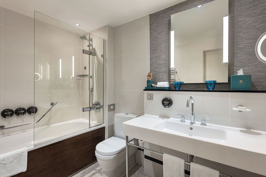 A modern bathroom with a glass-enclosed shower, a white sink, and a large mirror.
