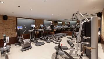 Uma academia moderna com diversos equipamentos de cardio, aparelhos de musculação e um amplo painel de espelhos.