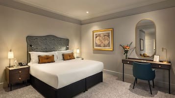 Een keurig opgemaakt slaapkamer met een groot bed, nachtkastjes, een bureau en een spiegel.