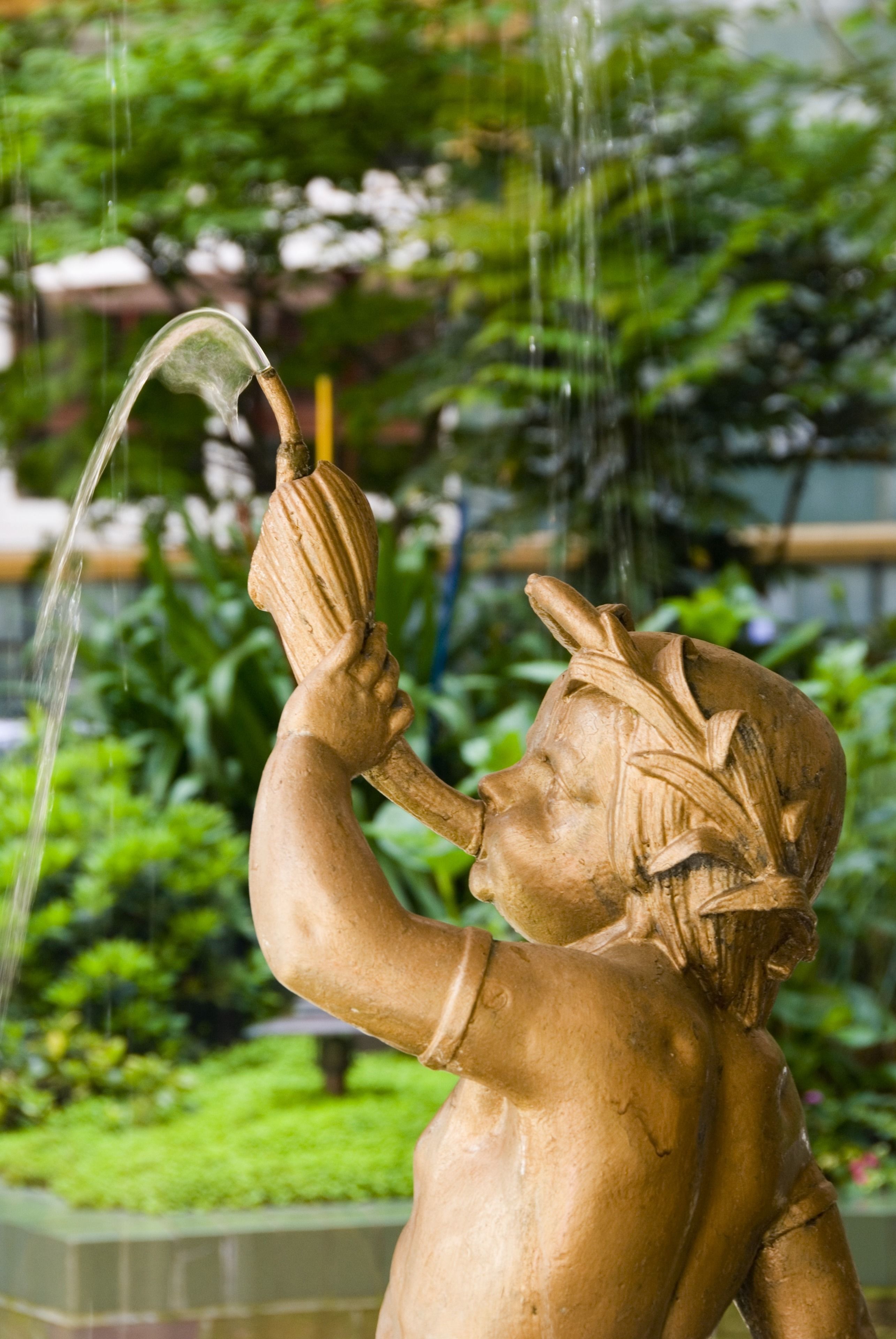 A bronze statue of a figure holding a shell with water flowing from its hand.