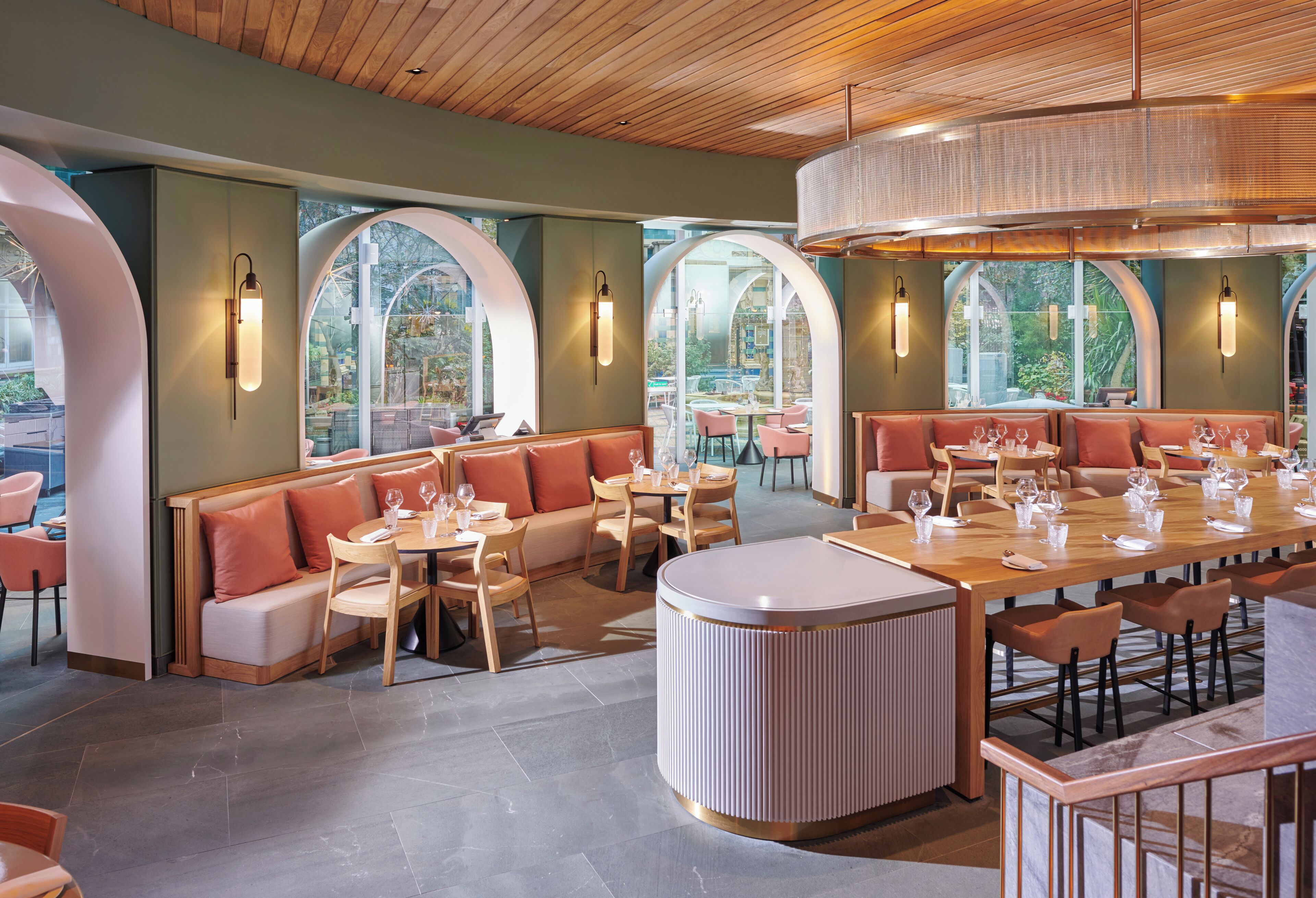 A restaurant interior with high arched windows, wooden ceiling, and modern furnishings.