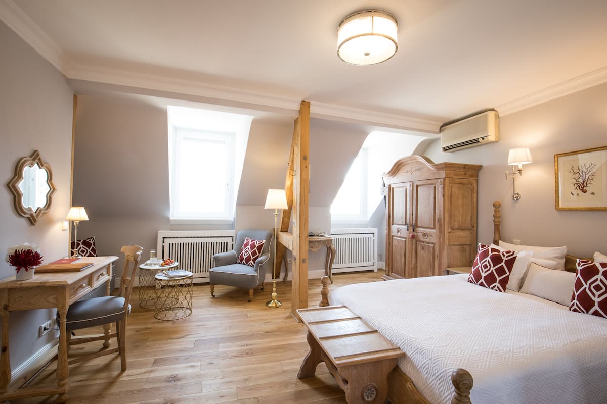 Une chambre à coucher avec un grand lit, un bureau en bois, une chaise, une petite table et un radiateur.