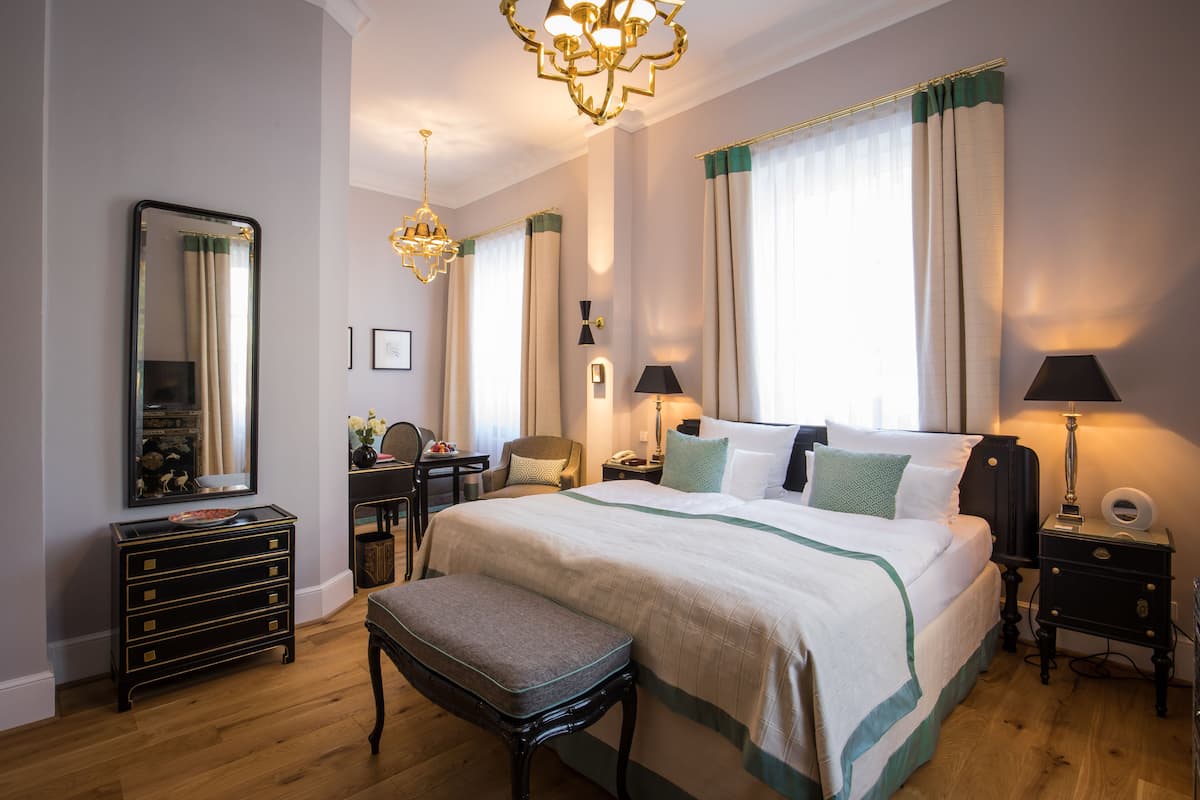 Une chambre d’hôtel bien aménagée, avec un grand lit, des tables de chevet, un bureau et un miroir.