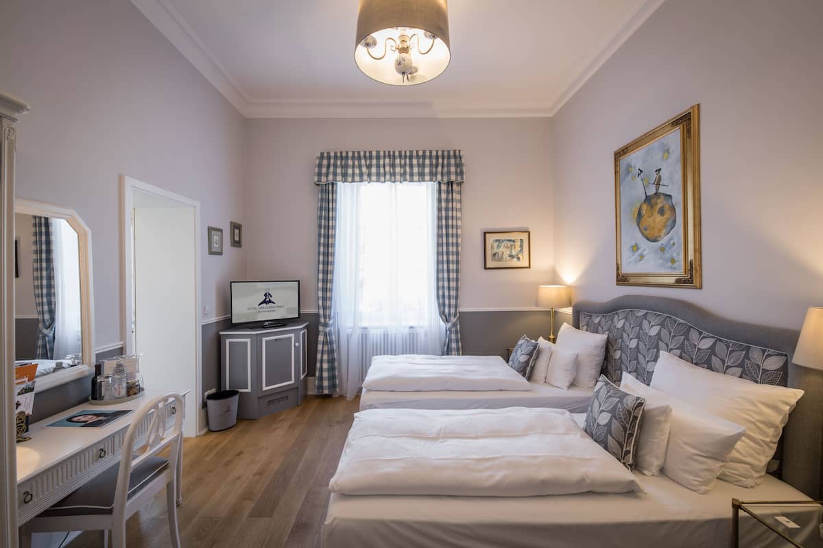 Une chambre d’hôtel avec deux lits, un bureau, une télévision et une grande fenêtre avec des rideaux.