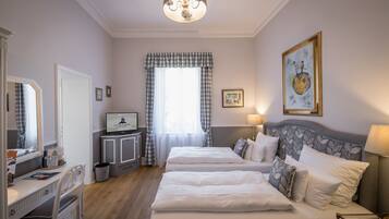 Hotelkamer met twee bedden, een bureau, een televisie en een groot raam met gordijnen.