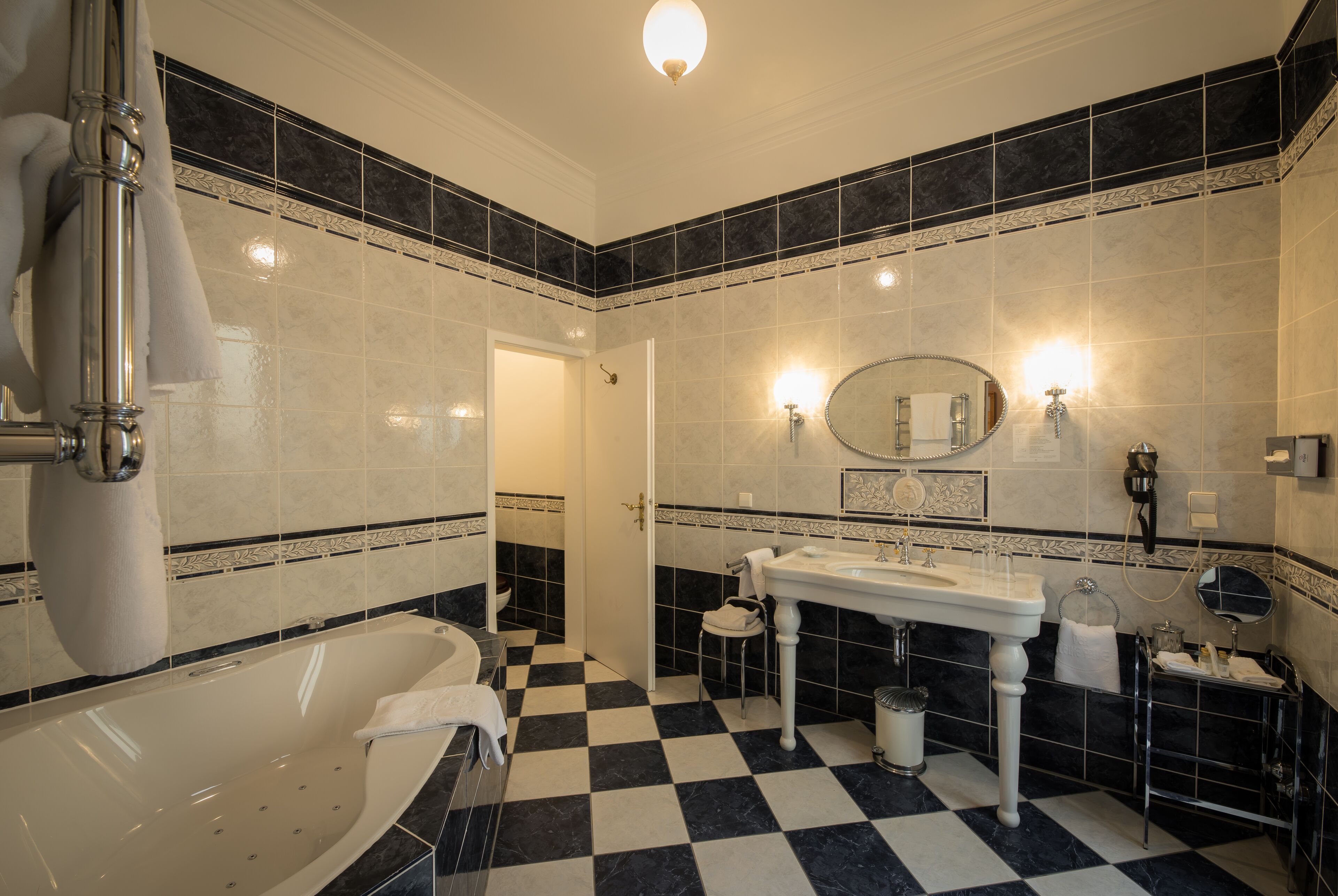 Un baño con piso a cuadros, una bañera, un lavamanos y un espejo.