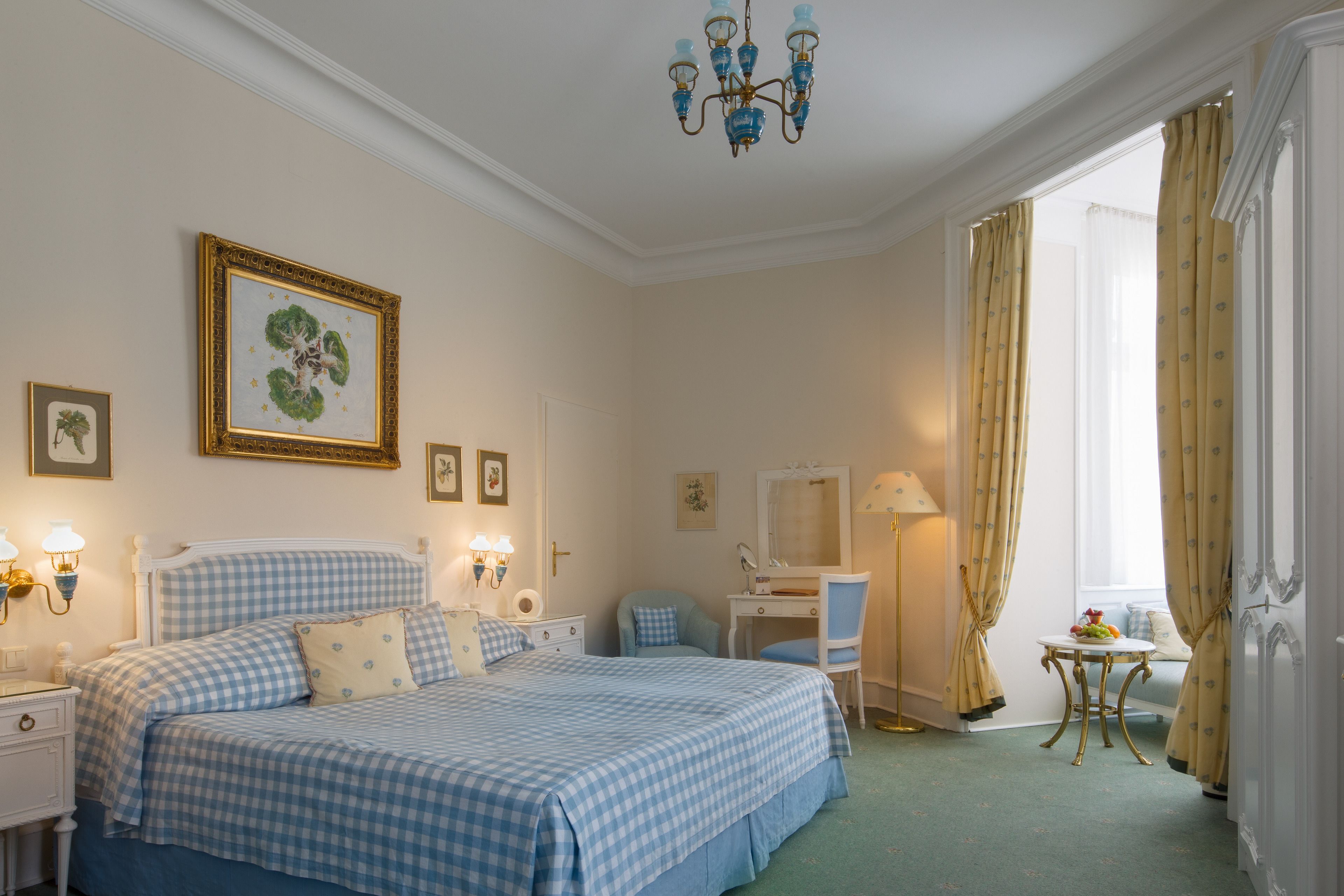 A bedroom with a bed, bedside tables, a desk, a chair, and a window with curtains.