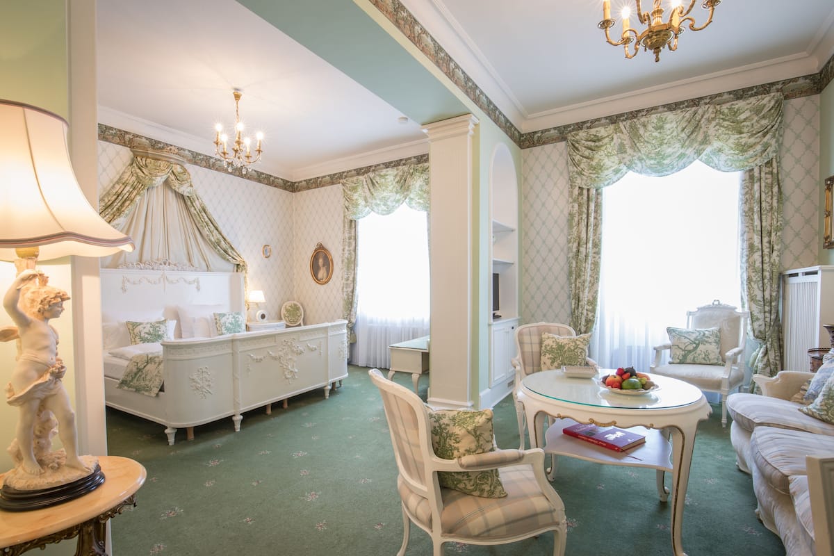 Une pièce avec une moquette verte, des meubles blancs et un papier peint à motifs floraux.