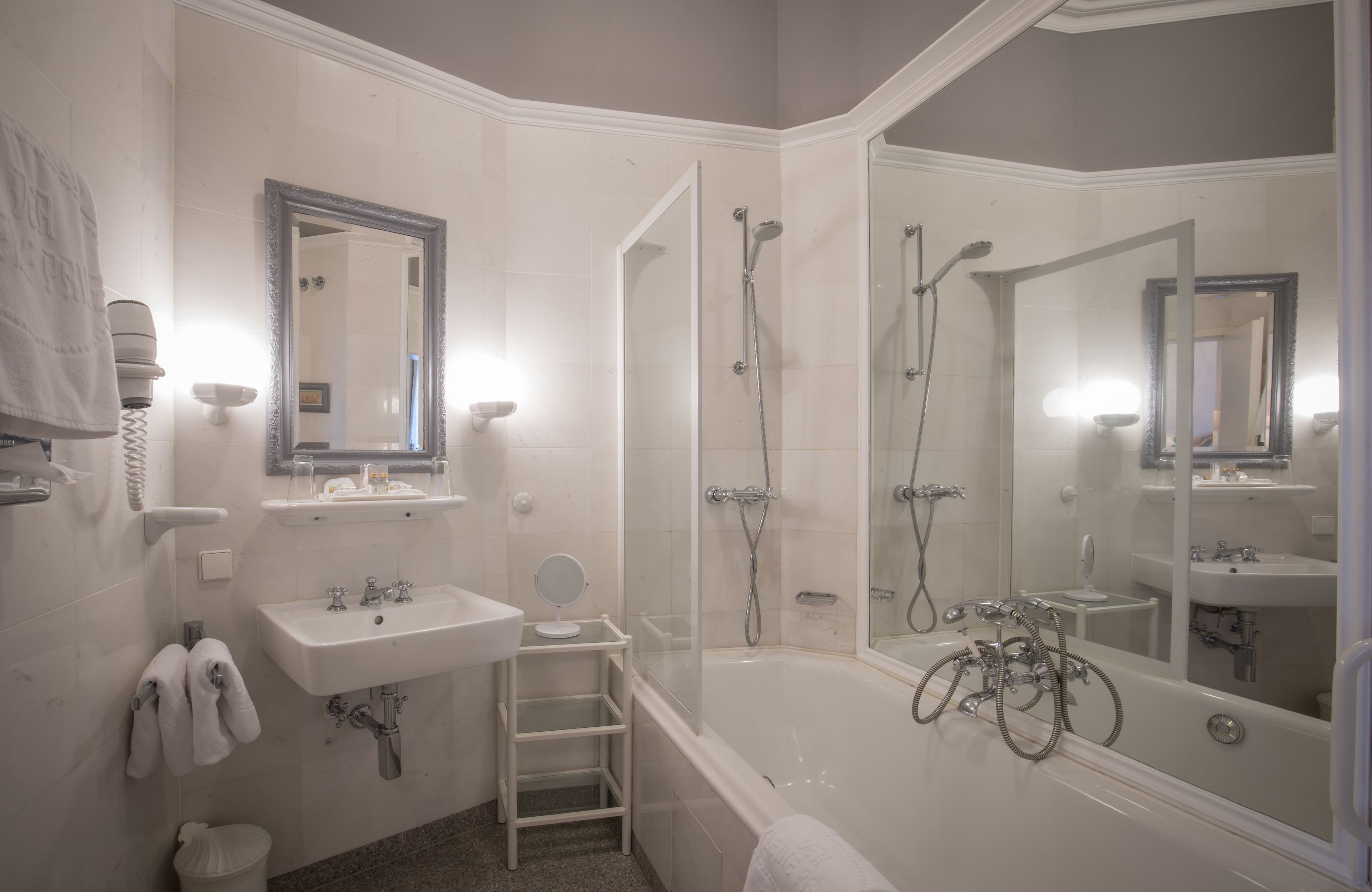 A modern bathroom with a bathtub, a shower, a sink, and a mirror.