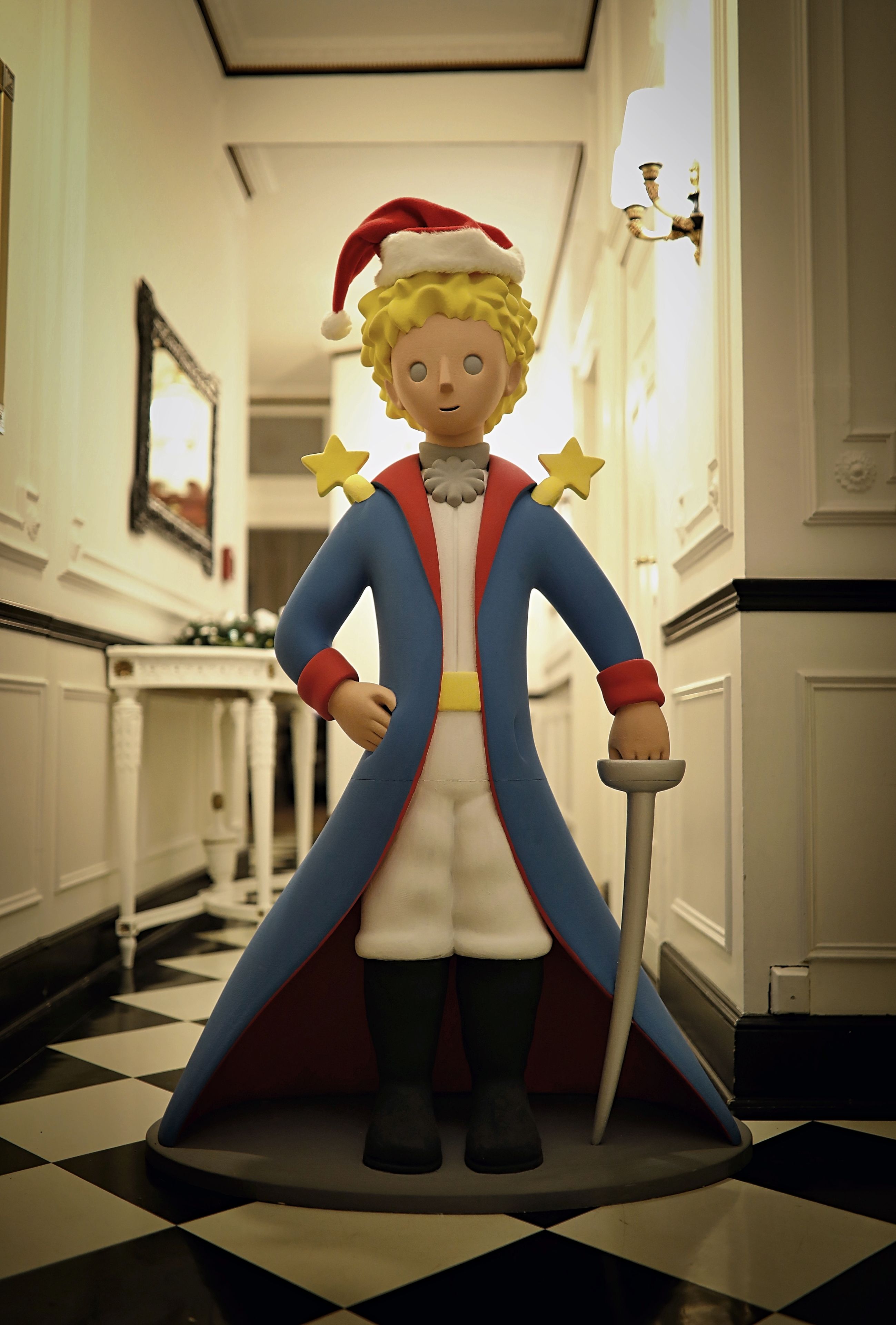 A figure in a red and blue costume with a star on the chest, standing in a hallway with a checkered floor and white walls.