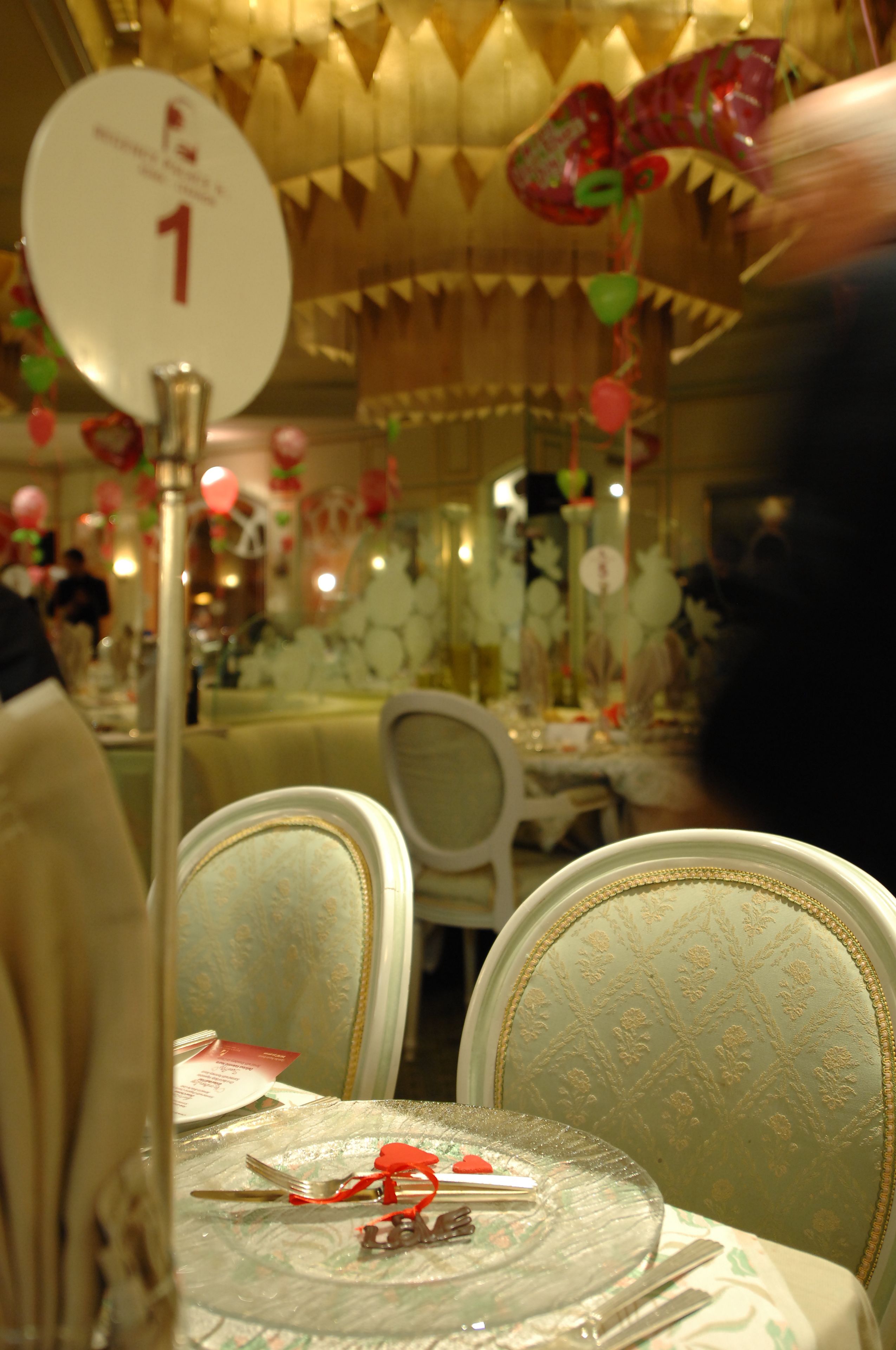 Un comedor con una mesa preparada para dos, sillas con tapicería estampada y un techo decorativo.