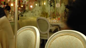 Un comedor con una mesa preparada para dos, sillas con tapicería estampada y un techo decorativo.
