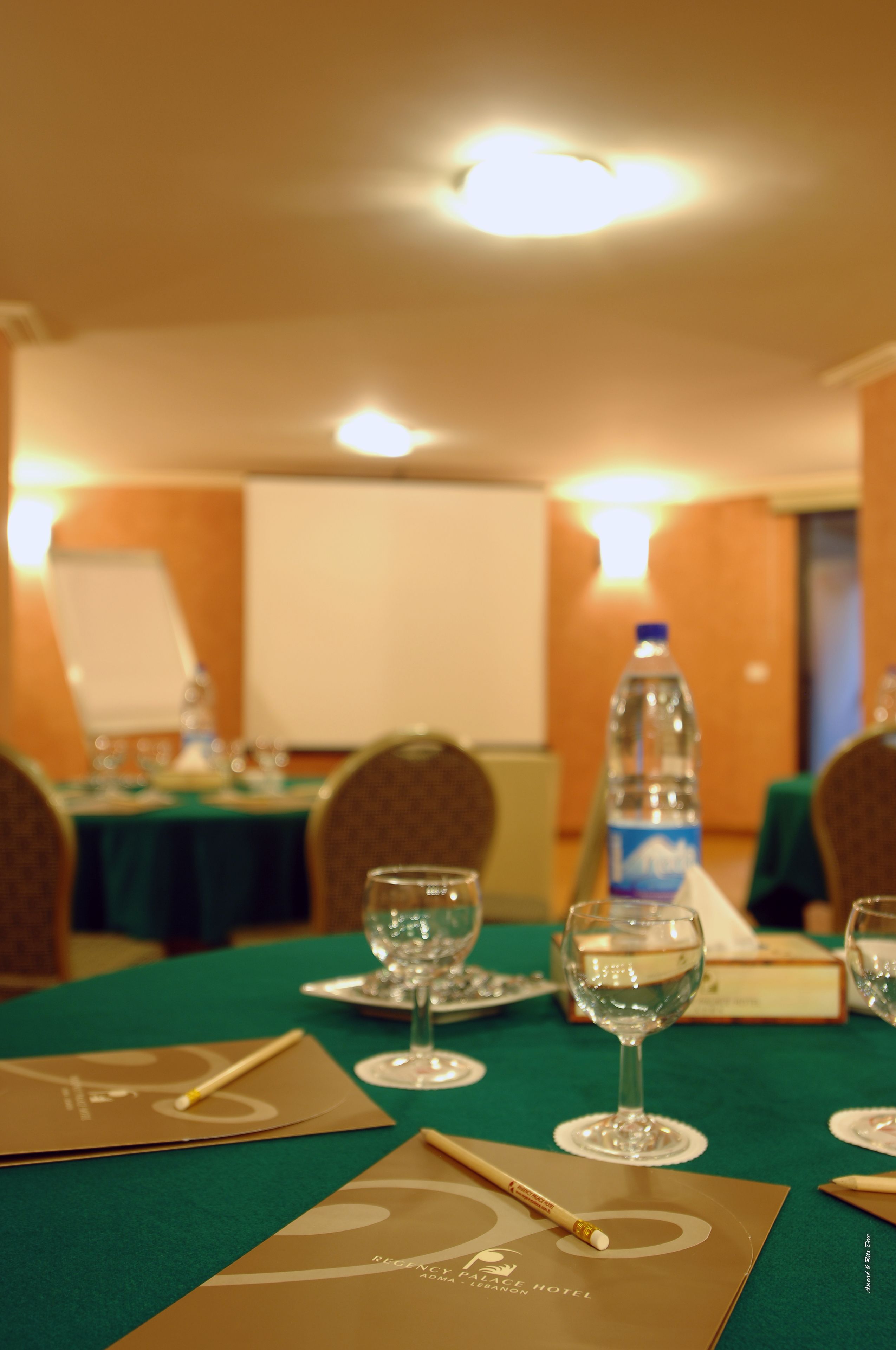 A conference room with tables set for a meeting, equipped with water bottles, glasses, and name cards.