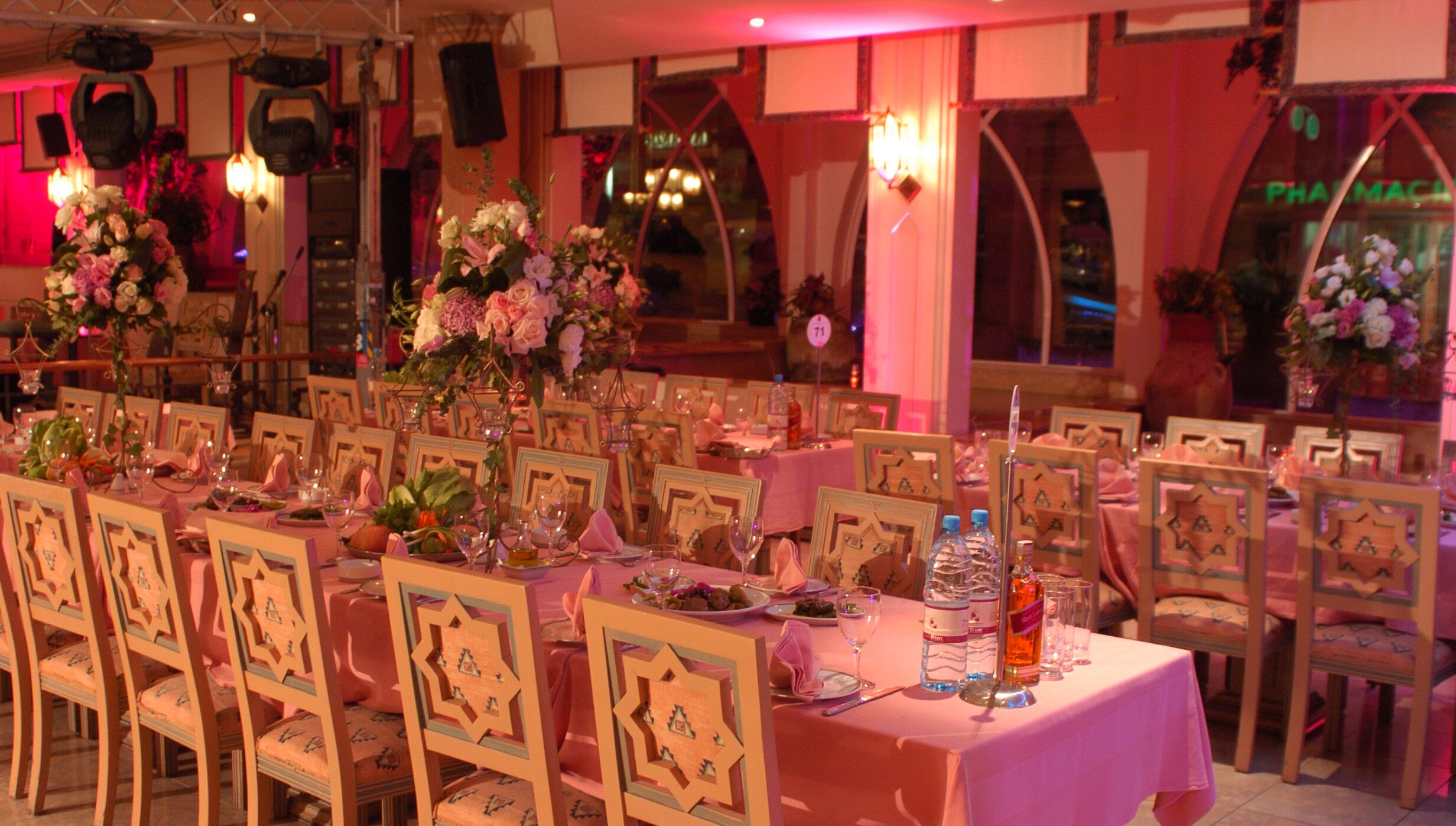 Un salón de banquetes con mesas redondas dispuestas para comer, cada una con centros de flores y cubertería.