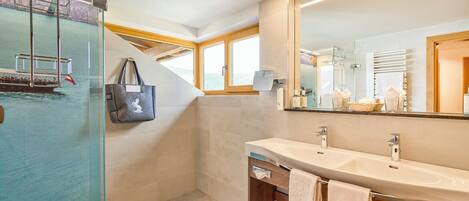 A modern bathroom with a glass-enclosed shower, a large mirror, and a wooden vanity.