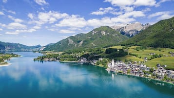 A lakeside town with a church, houses, and mountains in the background.