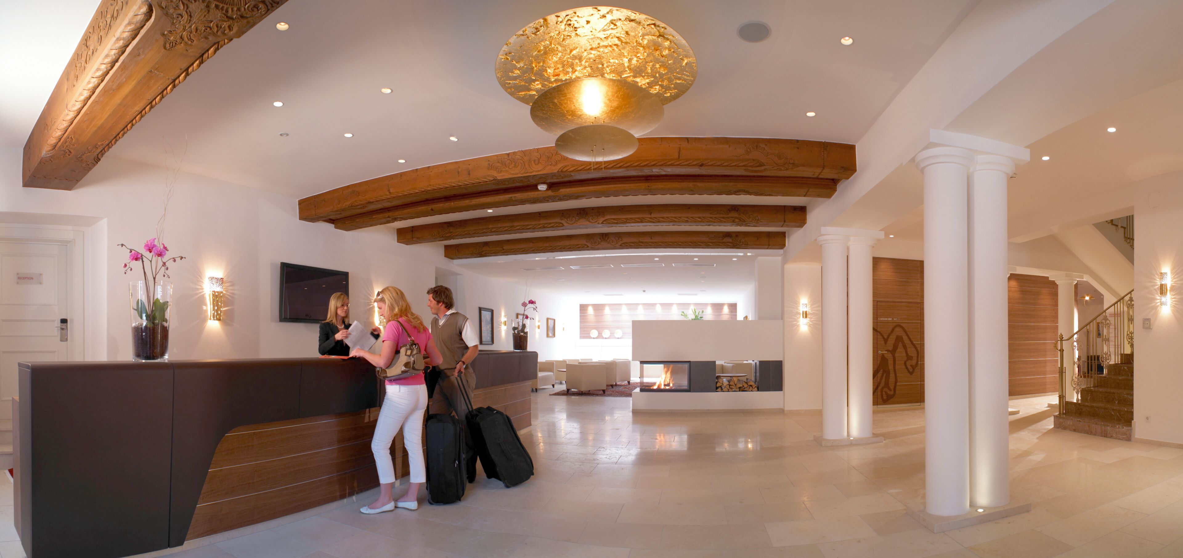 A reception area with a wooden reception desk, a fireplace, and a staircase.
