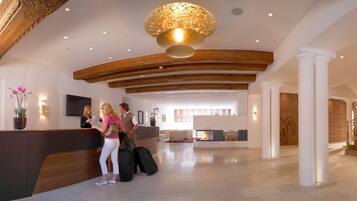 A reception area with a wooden reception desk, a fireplace, and a staircase.