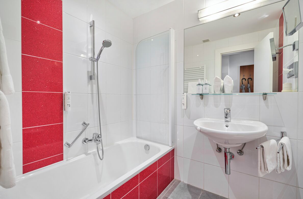 A modern bathroom with a bathtub, shower, and sink.