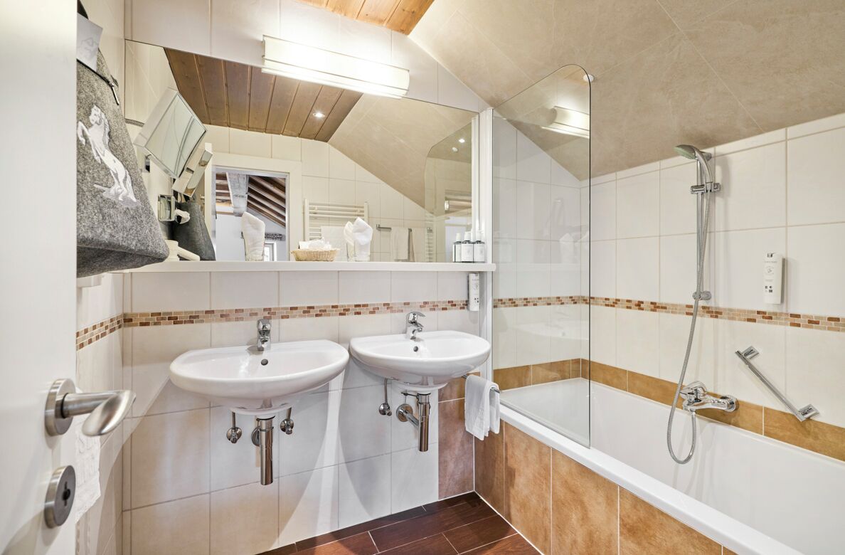 A bathroom with two sinks, a shower, and a mirror.