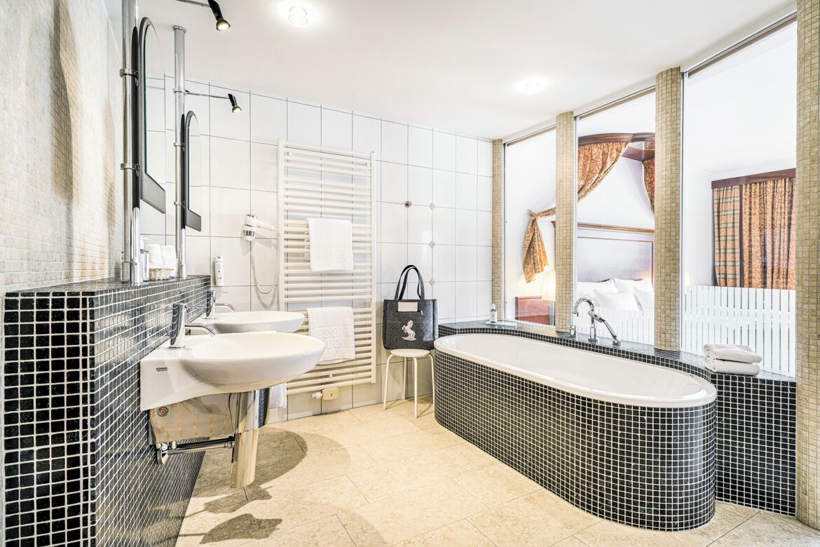 Uma casa de banho moderna com uma banheira grande, duas pias e uma cómoda.