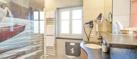 A modern bathroom with a large mirror, a sink, a towel rack, and a window.