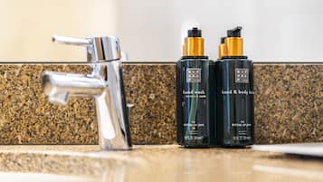 A bathroom with a granite countertop, a chrome faucet, and two bottles of hand and body lotion.