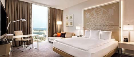 Habitación de hotel con una cama grande, un escritorio, una silla, un sofá y vistas a la ciudad.