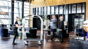 A modern lobby with a reception desk, seating areas, and a large window providing natural light.