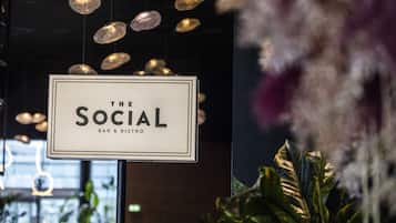 A sign for 'The Social Bar & Bistro' with hanging pendant lights and indoor plants.