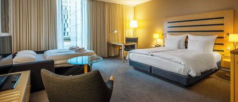 Een hotelkamer met een bed, twee fauteuils, een bureau en een kleine tafel.