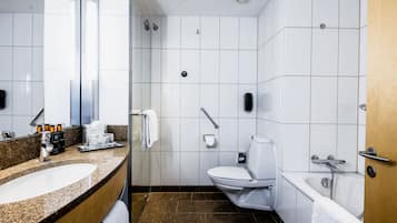 Un baño moderno con lavamanos de granito, inodoro blanco, bañera y ducha.