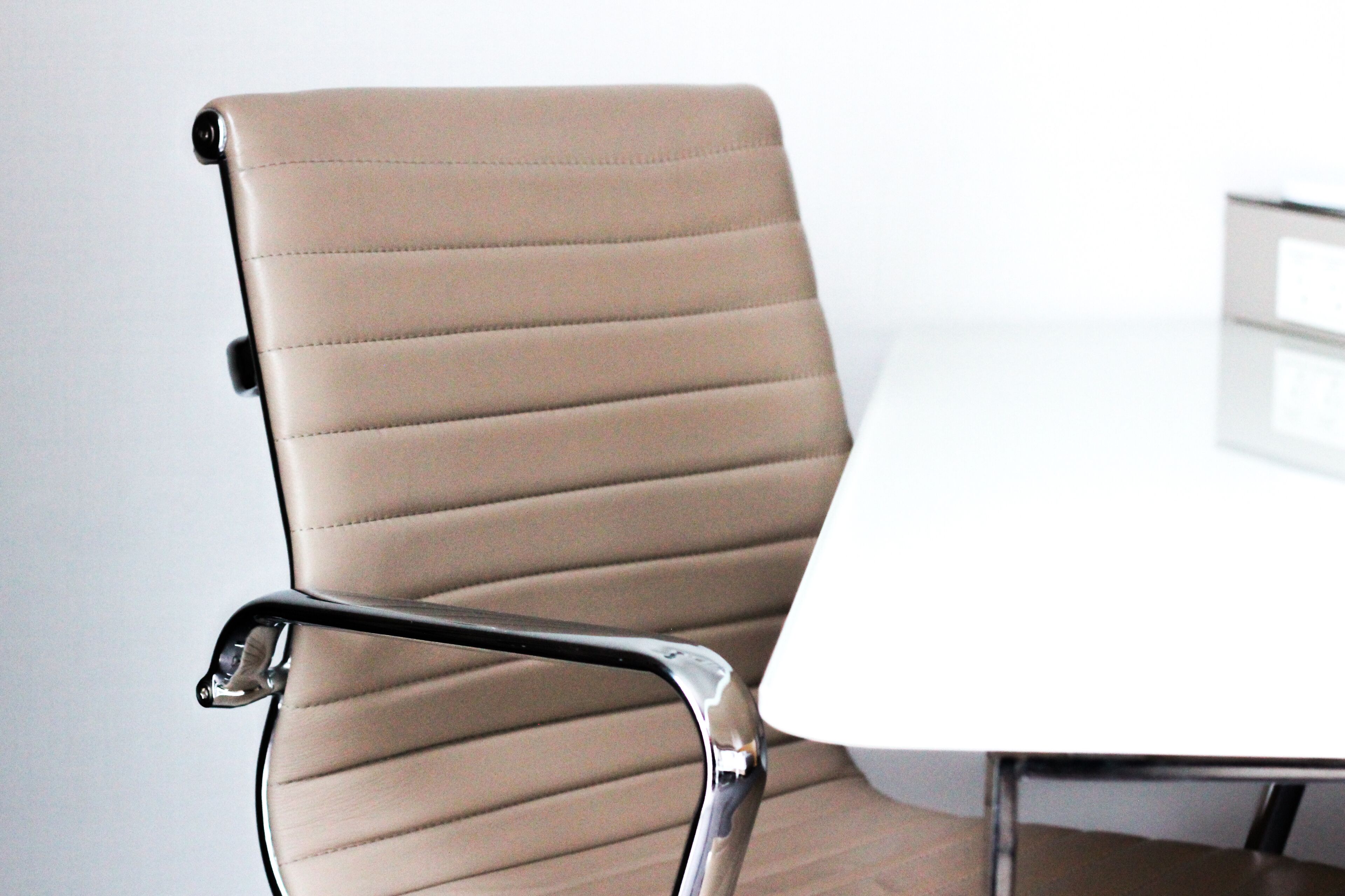 A chair with a high backrest and armrests, positioned next to a white table.