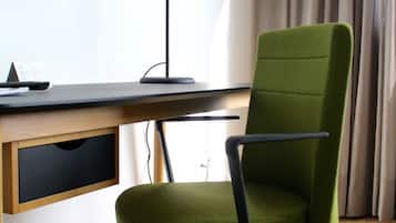 Una silla de oficina moderna con ruedas, un escritorio, una lámpara y un televisor montado en la pared.