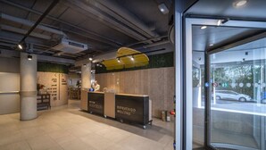 A reception area with a reception desk, a green sign, and a view of the street outside. - ARTIEM Madrid Hotel (Madrid)